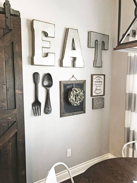 una bella parete della galleria della cucina della fattoria con grandi lettere, posate di metallo, un paio di segni e una ghirlanda su un pezzo di lavagna