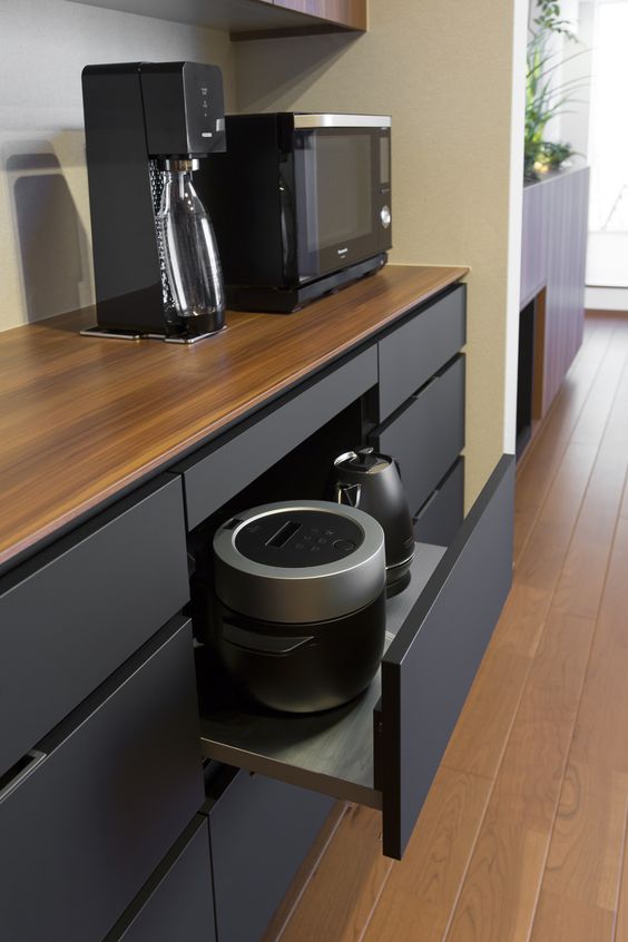 una cucina nera minimalista con un cassetto di grandi dimensioni con elettrodomestici neri mantiene la cucina più ordinata e ordinata