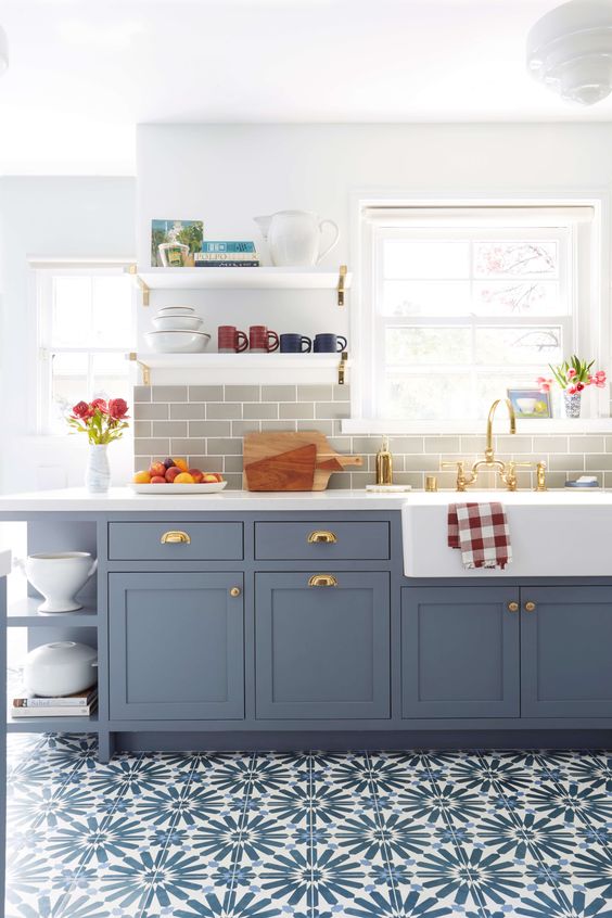 una cucina lineare blu a una parete con un backsplash in piastrelle della metropolitana grigia e un pavimento in piastrelle blu stampate più tocchi dorati è wow