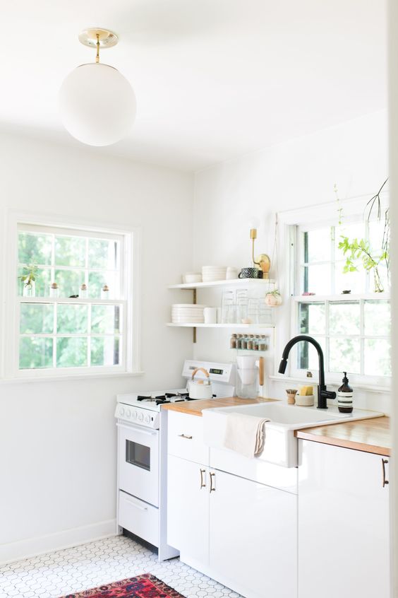un'elegante cucina lineare bianca a una parete con ripiani in macellaio e infissi neri, un pavimento piastrellato e un tappeto audace