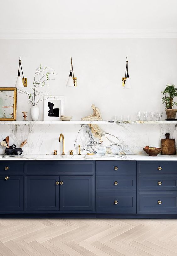 una cucina lineare blu navy con un alzatina in pietra bianca e controsoffitti, una mensola in pietra e applique è super chic