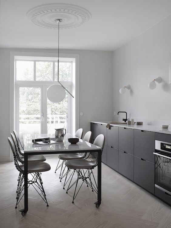 una cucina lineare scandinava nera a una parete con un controsoffitto bianco e infissi neri più alcune applique e una lampada a sospensione