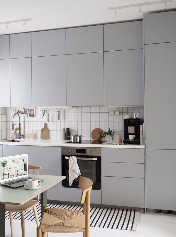 un'elegante cucina grigia contemporanea a una parete con un alzatina in piastrelle bianche e un piano di lavoro bianco è uno spazio chic
