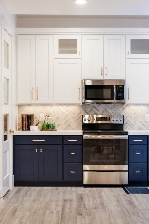 un'elegante cucina a una parete bianca e blu scuro con un alzatina in piastrelle grigie e un piano di lavoro in pietra bianca più luci integrate