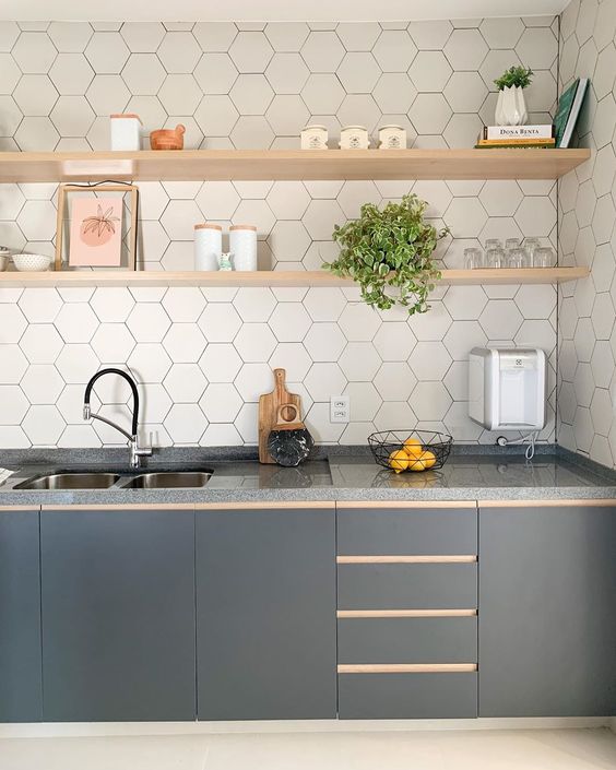 Un'elegante cucina lineare grigio grafite con un backsplash in piastrelle esagonali bianche e ripiani aperti in legno biondo