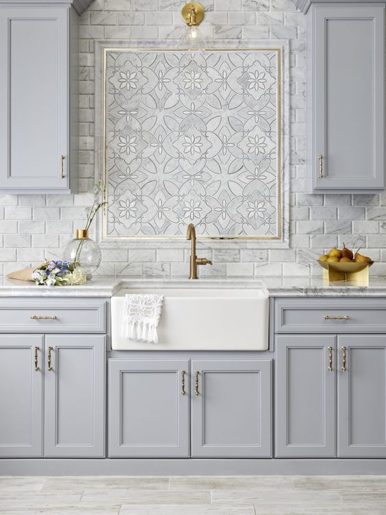 una cucina vintage grigio chiaro lineare con alzatina in piastrelle di marmo e ripiani in marmo più un bellissimo mosaico al centro