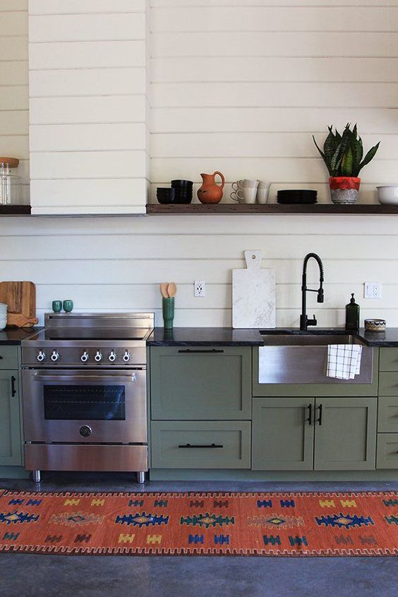 una cucina lineare verde vintage boho con ripiani neri, un backsplash bianco e una cappa in beadboard, un tappeto colorato