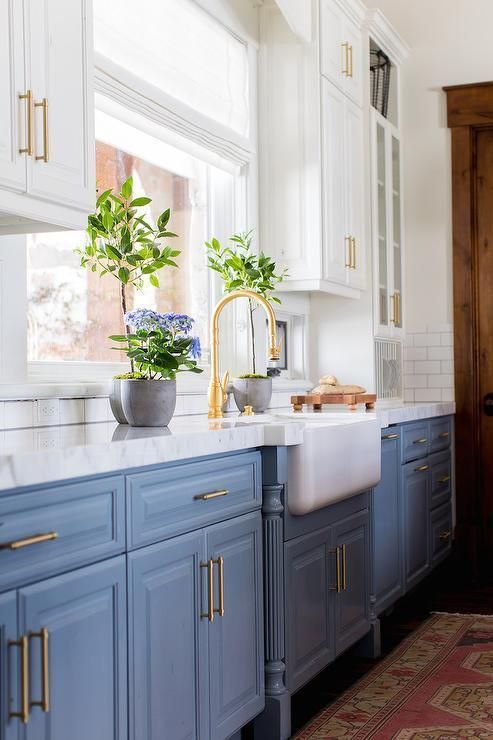 una cucina a parete bianca e blu vintage con ripiani in pietra bianca e alzatina in piastrelle bianche più tocchi dorati