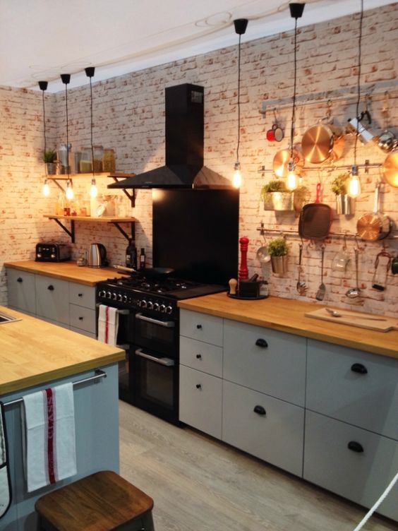 un'accogliente cucina contemporanea in colori neutri, con ripiani in macellaio e un muro in mattoni più un'isola cucina