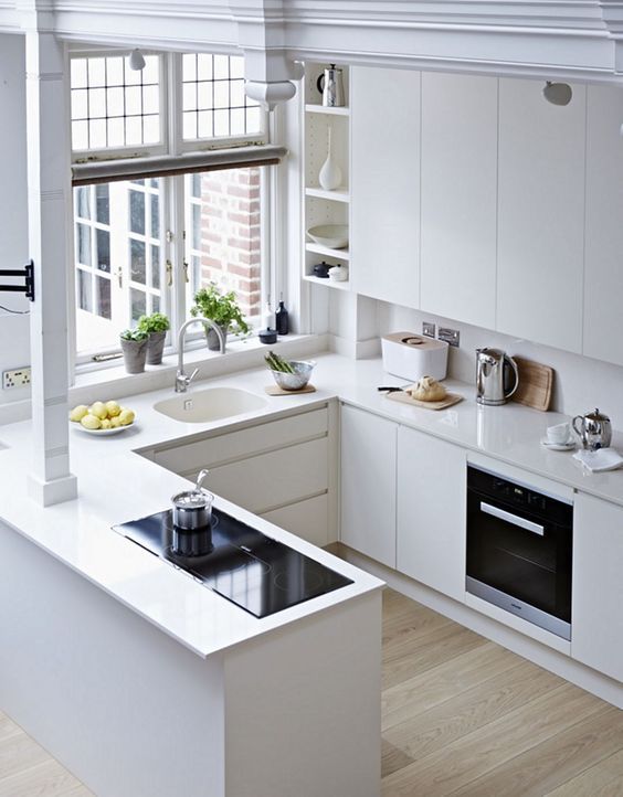 una cucina bianca minimalista a forma di U con controsoffitti abbinati e alzatina, con elettrodomestici incorporati
