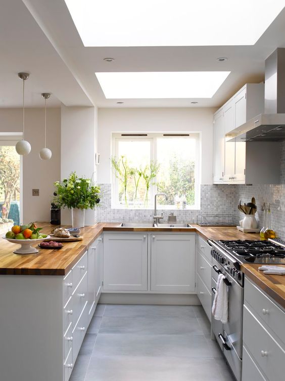 una cucina bianca con ripiani in macelleria, piastrelle a mosaico e lucernari è uno spazio molto arioso e accogliente
