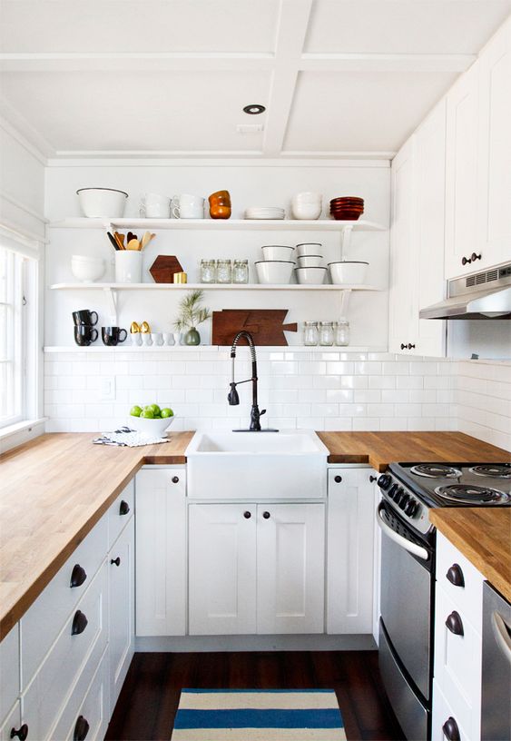 una cucina da fattoria bianca con ripiani in macelleria, alzatina in piastrelle bianche e infissi neri