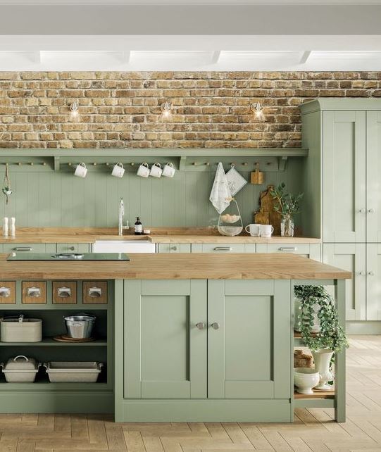 una cucina rustica verde salvia con eleganti mobili vintage, ripiani in legno e infissi e maniglie neutri
