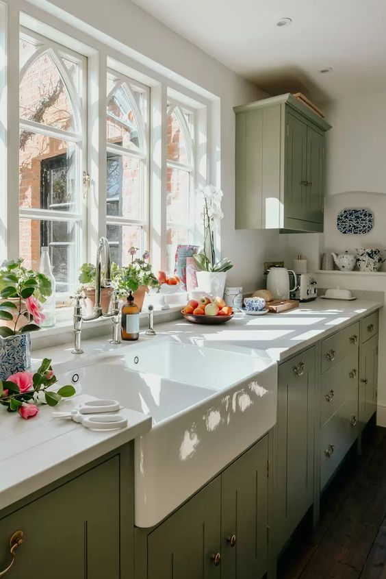 un'elegante cucina verde salvia vintage con ripiani in legno bianco e alzatina bianca, con infissi neutri è un'idea chic