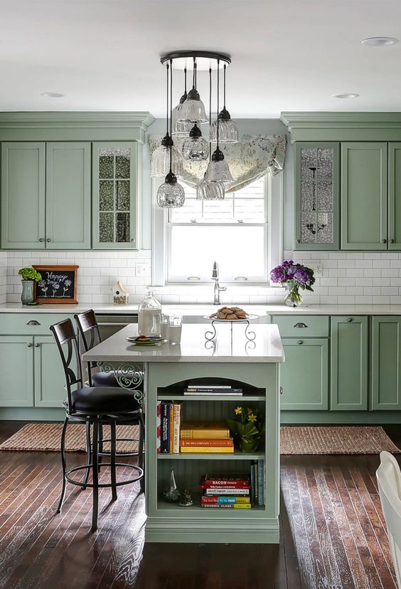 un'elegante cucina verde salvia vintage con mobili eleganti, un backsplash e controsoffitti in piastrelle bianche, una piccola isola da cucina con ripostiglio