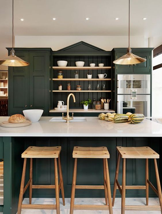una sofisticata cucina verde cacciatore con armadi vintage, mensole a giorno, ripiani bianchi, lampade a sospensione in metallo e sgabelli in legno