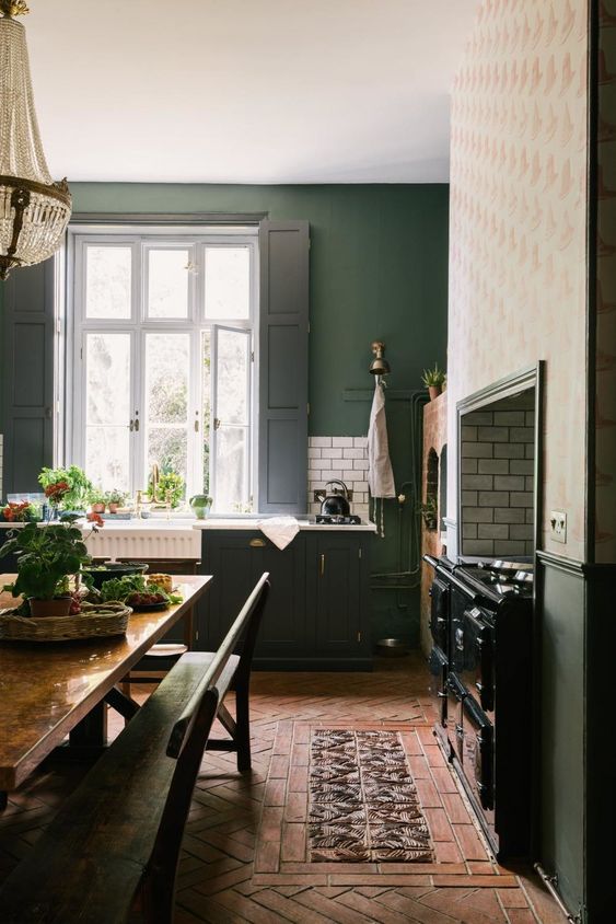 una cucina vintage verde cacciatore con una grande cucina vintage, ripiani bianchi e persiane nere e una sala da pranzo