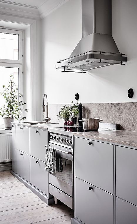 una cucina grigia scandinava con alzatina e controsoffitti in pietra grigia, infissi e pomelli neri
