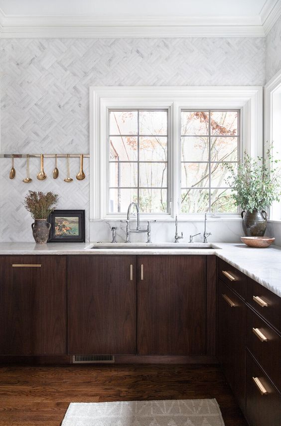una sbalorditiva cucina in noce con ripiani in pietra bianca e piastrelle in marmo bianco più tocchi d'oro