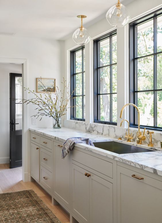 una raffinata cucina greige con un piano in marmo bianco e infissi dorati e un rubinetto è un'idea elegante