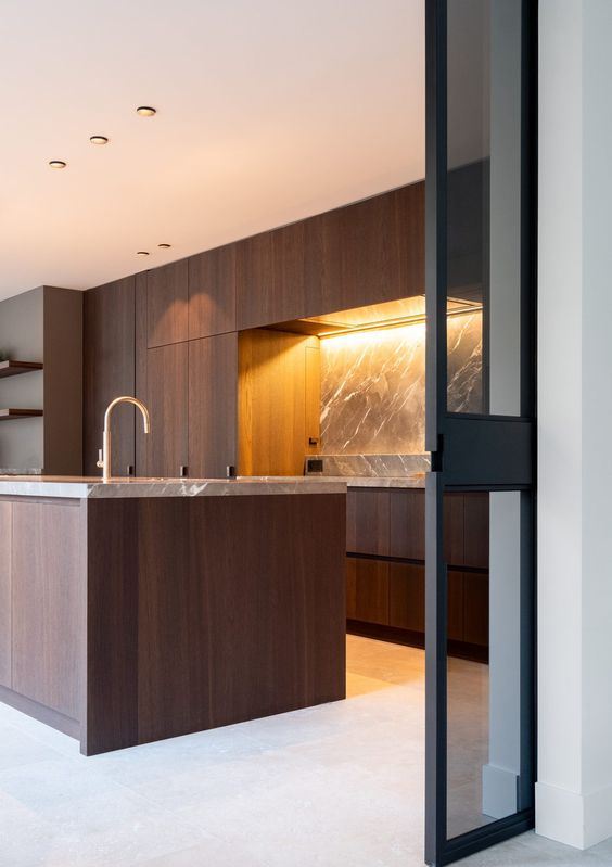 una cucina minimalista in noce con mobili eleganti, alzatina in marmo grigio e ripiani e infissi dorati