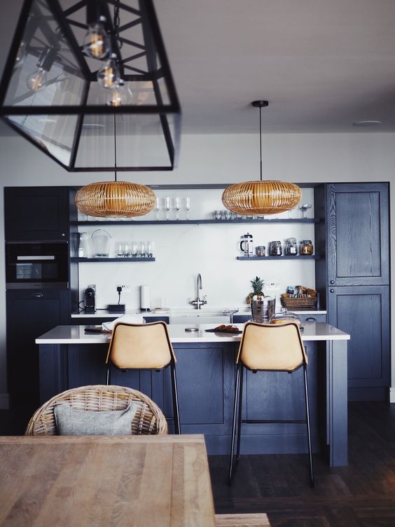 una fantastica cucina blu navy contemporanea con ripiani bianchi e alzatina, lampade in rattan e sgabelli in pelle