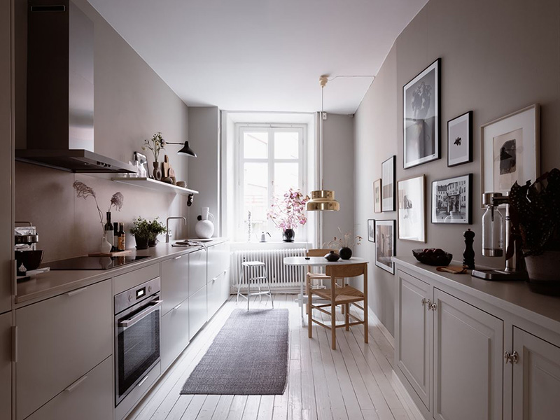 La cucina è realizzata con mobili moderni e vintage grigi, con un alzatina color malva e una grande parete della galleria