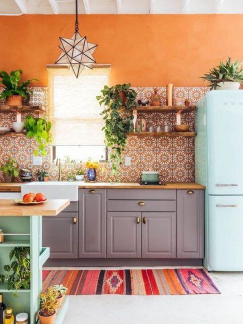 una cucina audace con ante grigie, un alzatina in piastrelle stampate arancione, un frigorifero blu menta e un'isola cucina più un tappeto colorato