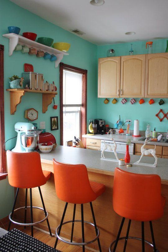 una cucina blu retrò con sgabelli arancioni e stoviglie colorate più tazze è uno spazio molto elegante e audace