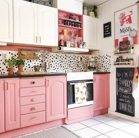 una cucina giocosa con mobili rosa e bianchi, alzatina Dolmatin e maniglie e infissi in ottone è audace e cool