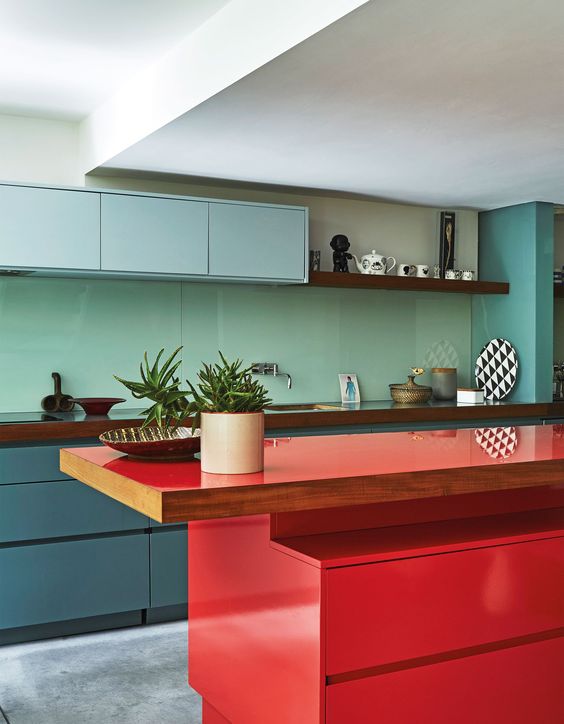 una cucina minimalista con armadi blu e blu tenui, un backsplash verde menta, un'isola da cucina rossa audace e controsoffitti in legno