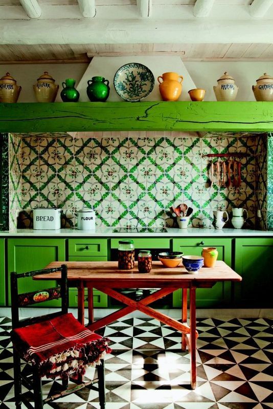 una cucina eclettica con ante verde intenso, piastrelle stampate luminose sul backsplash, un tavolo e una sedia in legno più stoviglie colorate