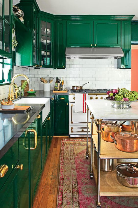 una cucina color smeraldo con un backsplash in piastrelle bianche della metropolitana, eleganti tocchi dorati e un luminoso tappeto boho