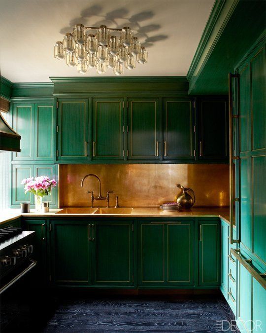 una cucina color smeraldo con alzatina e top dorati e un lampadario raffinato e chic è elegante e vintage