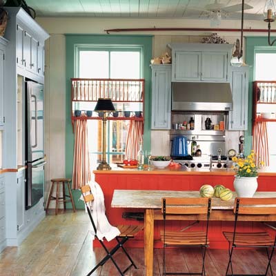 un'audace cucina vintage con pareti verdi, un'isola da cucina rossa, un mobile azzurro polvere, elettrodomestici in acciaio inossidabile e sedie arancioni