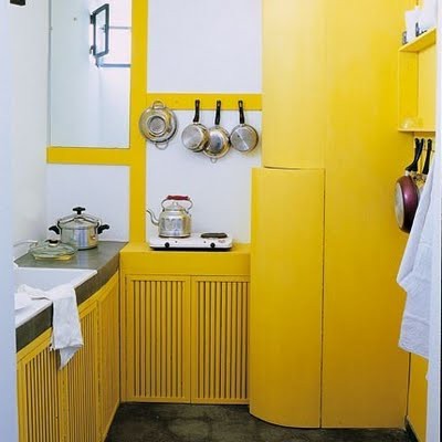 una cucina giallo limone con grandi piastrelle bianche e un pavimento di cemento ha un aspetto fresco e un aspetto molto audace