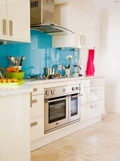 una cucina bianca con un backsplash blu lucido ed elettrodomestici in acciaio inossidabile è uno spazio elegante con un tocco audace
