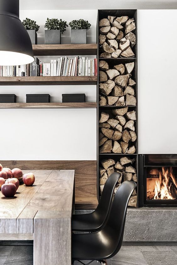 un camino integrato minimalista e un'unità di stoccaggio aperta con legna da ardere per riscaldare e rallegrare uno spazio minimalista