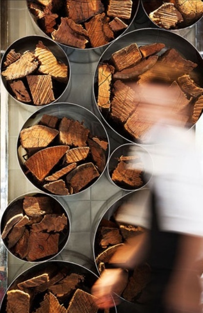 un moderno e laconico contenitore a parete di tubi metallici può essere utilizzato non solo per la legna da ardere ma anche per altre cose ed è allo stesso tempo un elemento decorativo