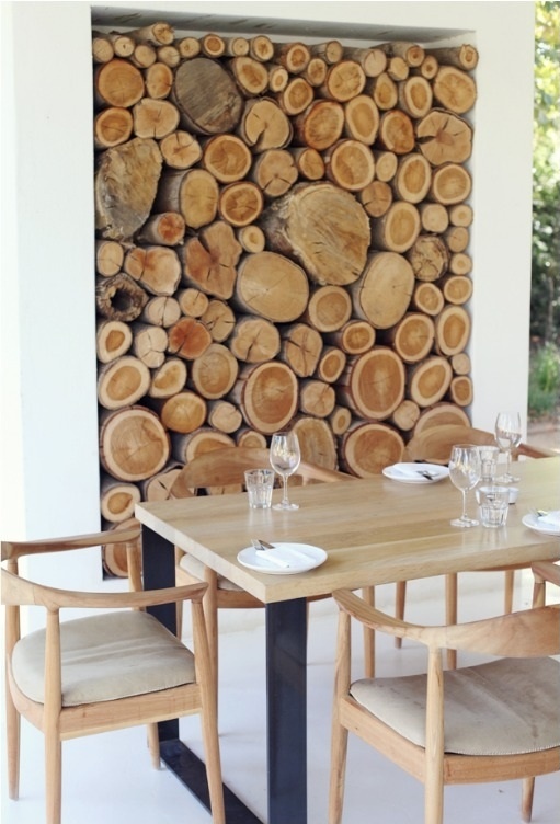 una nicchia con legna da ardere come elemento decorativo per una sala da pranzo all'aperto, per collegarla alla natura e renderla accogliente