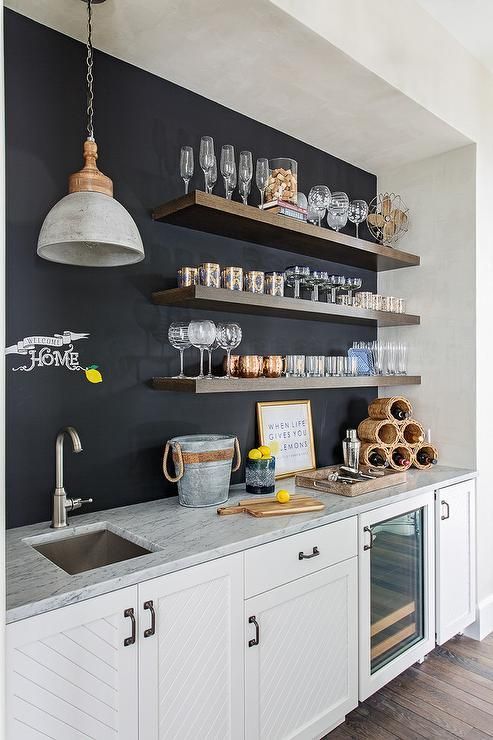 una moderna cucina neutra con una parete lavagna, scaffali aperti e una lampada a sospensione è uno spazio elegante e alla moda