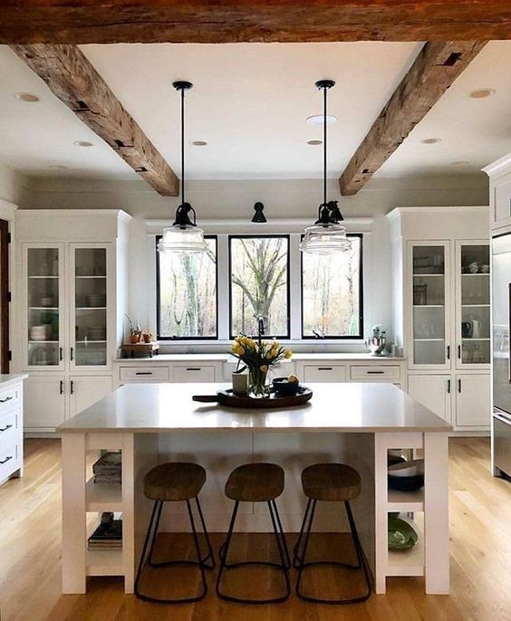 una cucina bianca pulita con travi in ​​legno grezzo che aggiungono calore e intimità allo spazio e lo rendono accattivante
