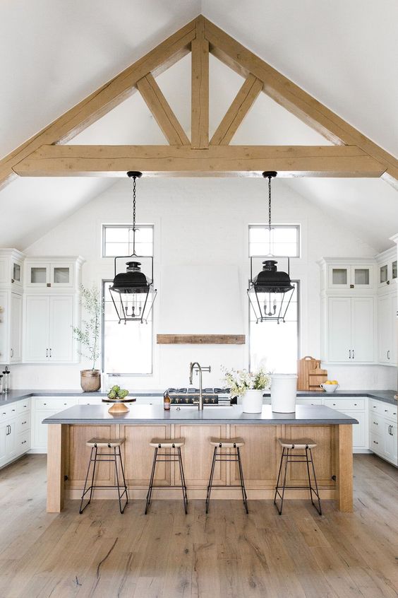 una cucina contemporanea neutra con ripiani in pietra scura, travi in ​​legno, una cucina in legno è accogliente ed elegante