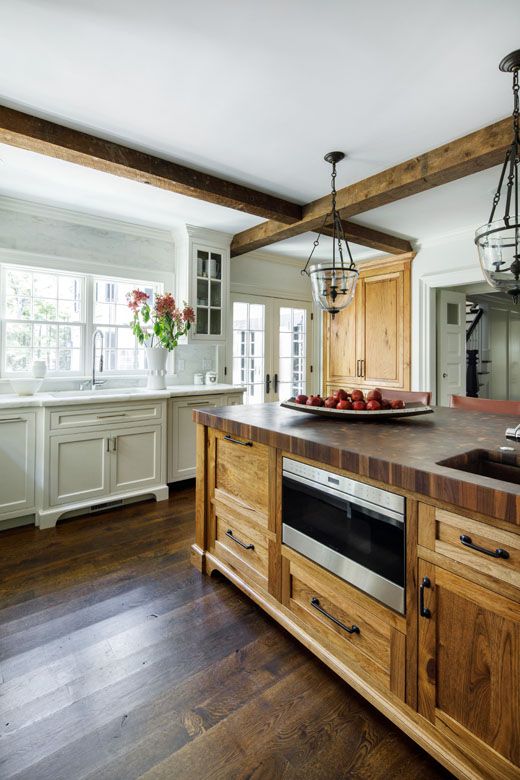 una cucina vintage con armadi neutri, un'isola della cucina in legno colorato e travi in ​​legno che si abbinano e sembrano accoglienti
