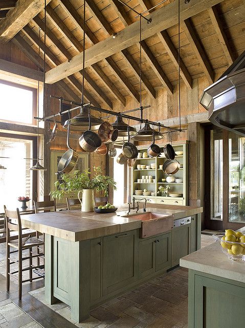 una cucina rustica con mobili verdi, ripiani in legno e pietra, un soffitto in legno con travi a vista è uno spazio chic