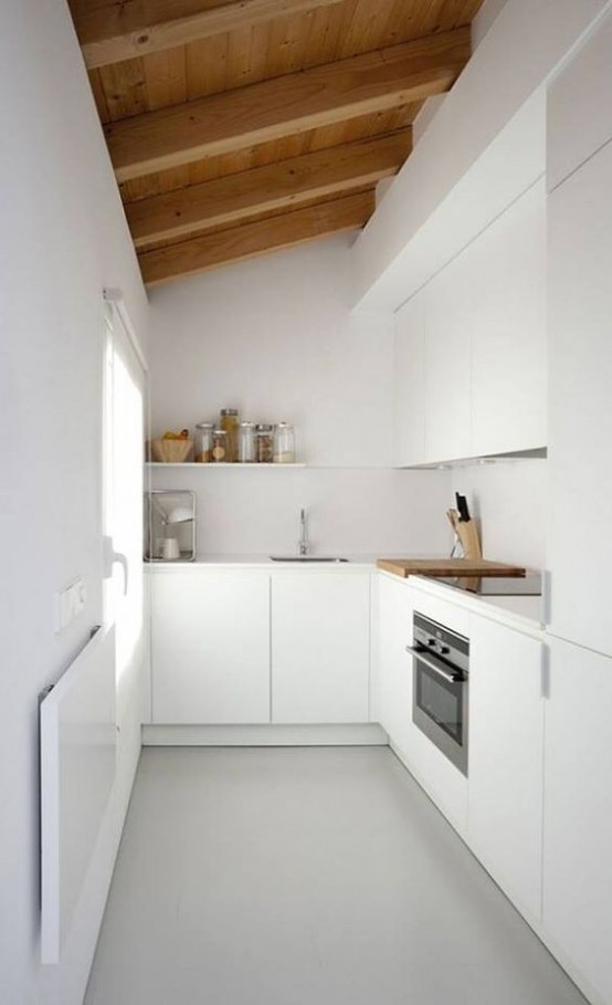 una cucina bianca minimalista con mobili eleganti, un soffitto in legno con travi in ​​legno che ammorbidisce e riscalda lo spazio e lo rende interessante