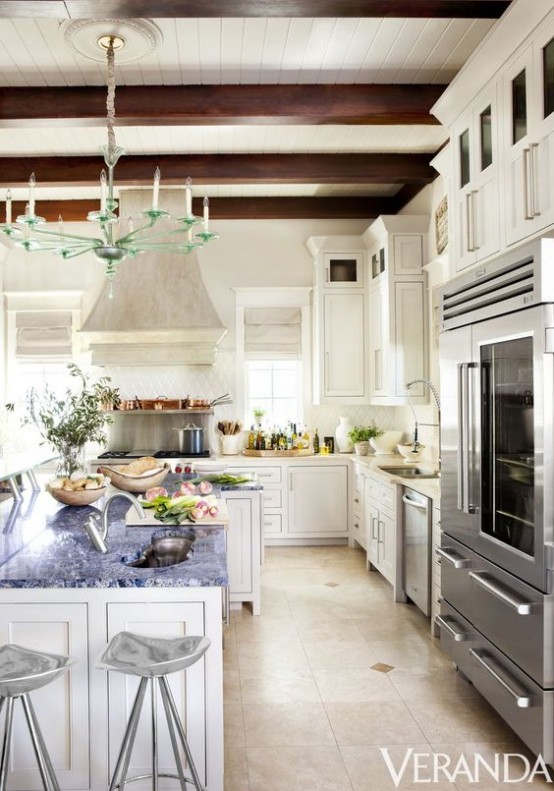 un'elegante cucina vintage bianca con mobili chic, una grande isola della cucina, sgabelli chic, travi in ​​legno scuro per un tocco raffinato e un lampadario in vetro creativo