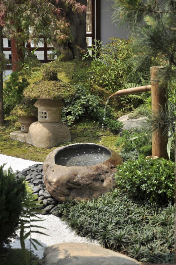 erba e vegetazione, ciottoli, una fontana in pietra e bambù, una lanterna in pietra e muschio per creare un incantevole spazio giapponese