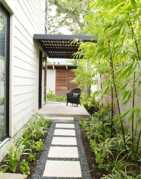 un cortile anteriore a bassa manutenzione con ciottoli, piastrelle, vegetazione e bambù è un'idea adorabile per una casa moderna