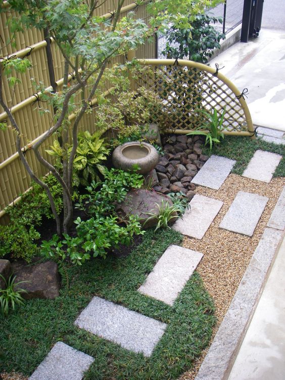 erba, piastrelle di cemento, arbusti, un albero sottile, una fontana con ciotola di stoen e rocce per un look di ispirazione giapponese adorabile e chic